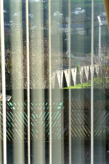 Day of the Rat (2010)&nbsp;1800 x 1200 x 40mm. Ultra slim LED lightbox, Duratran '...In&nbsp;Day of the Rat, a photographic image presents the view through the blinds of a window, overlooking an imposing concrete bunker. At a formal level, one notes the voyeuristic arrangement of the scene, the artist's gaze from the periphery, from the inside of the house, onto the landscape. The anecdotal subtext adds another layer, however, re-visiting the political history of Northern Ireland from a contemporary, post-Troubles perspective. Morris had been asked to sort out a dead rat, decomposing underneath the floorboards of his mother's house. Having called in professional exterminators, who were engaged in cutting holes in the&nbsp;floor while trying to 'sniff out' the corpse, the artist and his family retreated to the upstairs bedroom. Here, his eye was caught by the glare of sunlight through the window and a glimpse through the shutters of a cemetery outside. For Morris, the building's stark exterior, brutalist architecture and nearby floodlights recalled a prison camp and it is this (un) intentional misreading that can be seen to bridge the two divides of his practice. The correspondence between cemetery and floorboards, the artist sequestered in his mother's bedroom while 'interpreting' the building as a prison, the uncanny charge of the past rushing into the present; through these accidents, one infers the legacy of the Troubles. It is Morris' attunement to such connections, and his ability to re-assemble and re-create that experience, that offers another, subtler reading. It is this anecdote that resists the overall, objective meaning and that states, without apology: &ldquo;I guess you had to be there.&rdquo;&nbsp;(text extract&nbsp;&lsquo;Practicing everyday life&rsquo; Chris Clarke,&nbsp;This Then, Locky Morris, Catalogue 2010 )