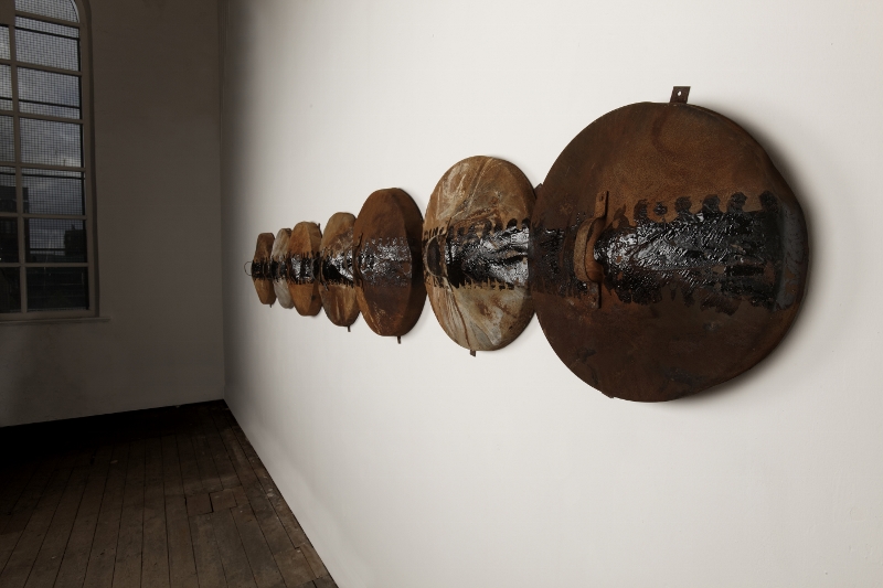 Gap of Danger - An Bhearna Bhaoil (1988) 56 x 14 x 450 cm. Burnt binlids, tar. Collection Wolverhampton Art Gallery and Museum